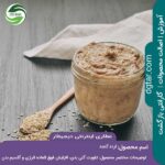 ارده کنجد در ظرف شیشه ای به همراه قاشق چوبی و کنجد در داخل قاشق و کنار آن